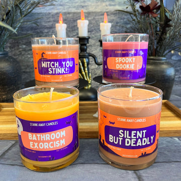 Picture of four candles on a halloween themed background. Text on the candles says Witch, You Stink!, Spooky Dookie, Bathroom Exorcism, Silent But Deadly.