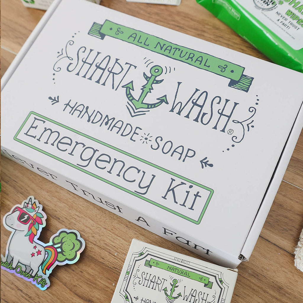 the contents of a shart wash emergency kit fathers day gift box on a wood background. 2 soap bars, 2 packs of shart wipes, soap bag and stickers.
