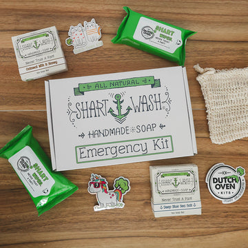 the contents of a shart wash emergency kit fathers day gift box on a wood background. 2 soap bars, 2 packs of shart wipes, soap bag and stickers.