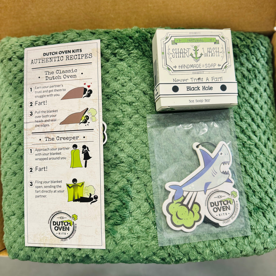 Green blanket with 'Dutch Oven Kits' recipe card, soap bar, and farting shark air freshener.