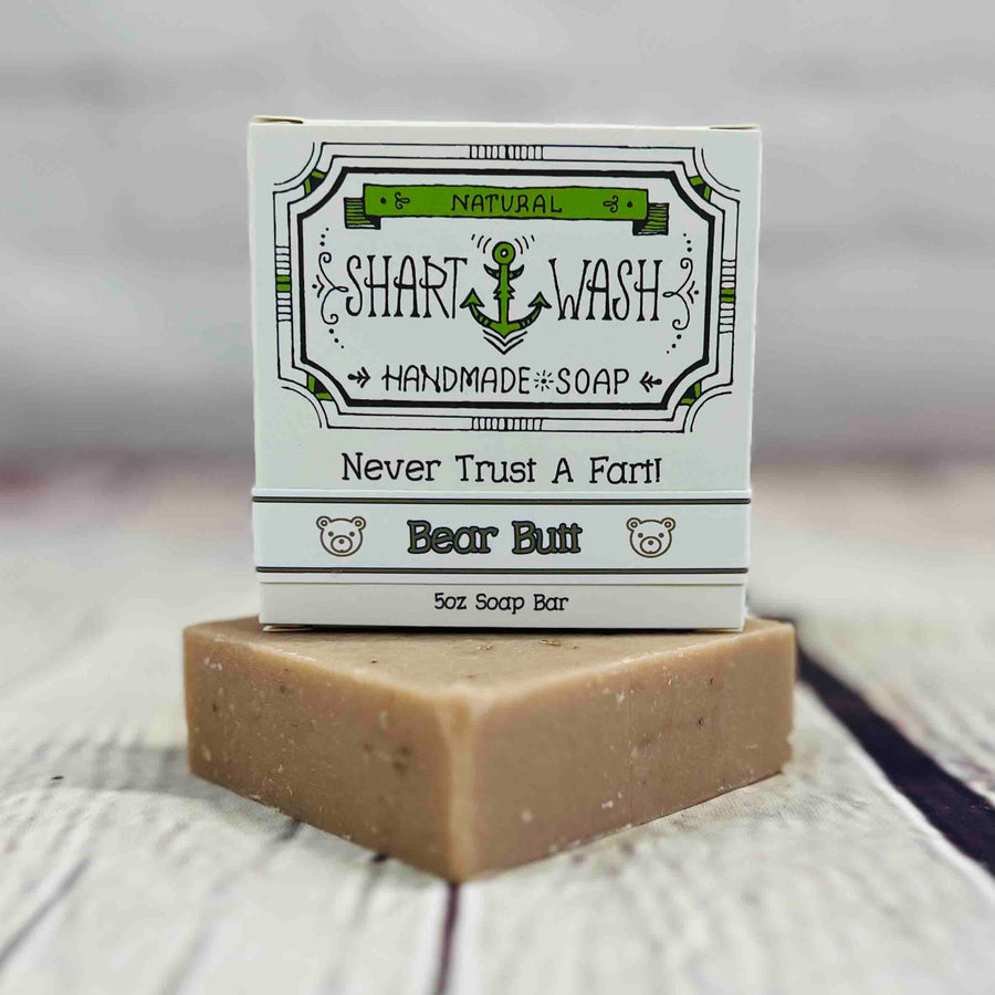 Picture of a box of Shart Wash Natural Handmade Bar Soap Bear Butt (oatmeal milk & honey) scent sitting on a tan bar of soap with a wood background