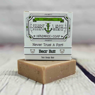 Picture of a box of Shart Wash Natural Handmade Bar Soap Deep Bear Butt oatmeal milk & honey scent sitting on a tan bar of soap with a wood background
