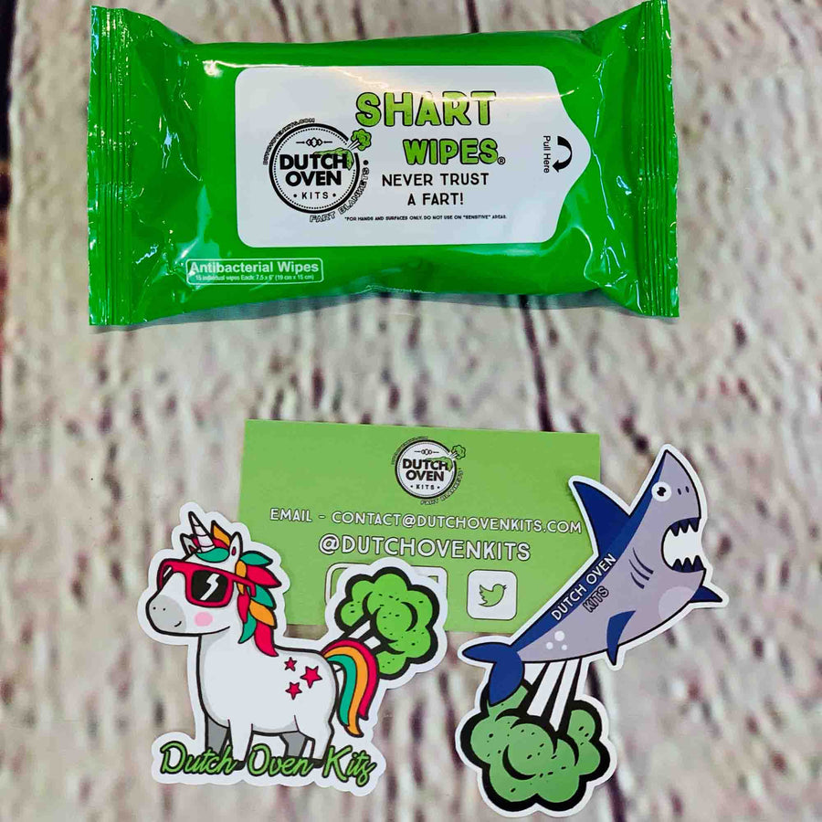 Picture of 1 pack of Shart Wipes antibacterial hand and surface wipes on a wood background with a business card, farting unicorn sticker and a farting shark sticker