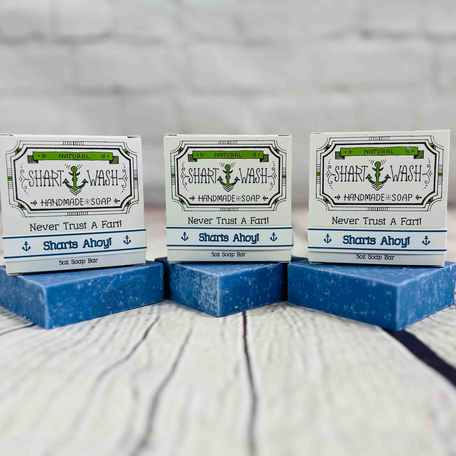 Picture of 3 boxes of Shart Wash Natural Handmade Bar Soap Deep Blue Sea Salt scent sitting on 3 blue bars of soap with a wood background