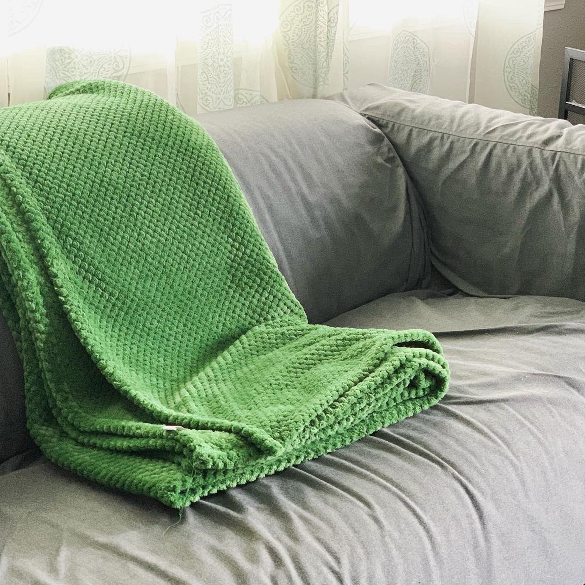 Image of a dark green color Microfiber fleece throw blanket draped over a bed and bench
