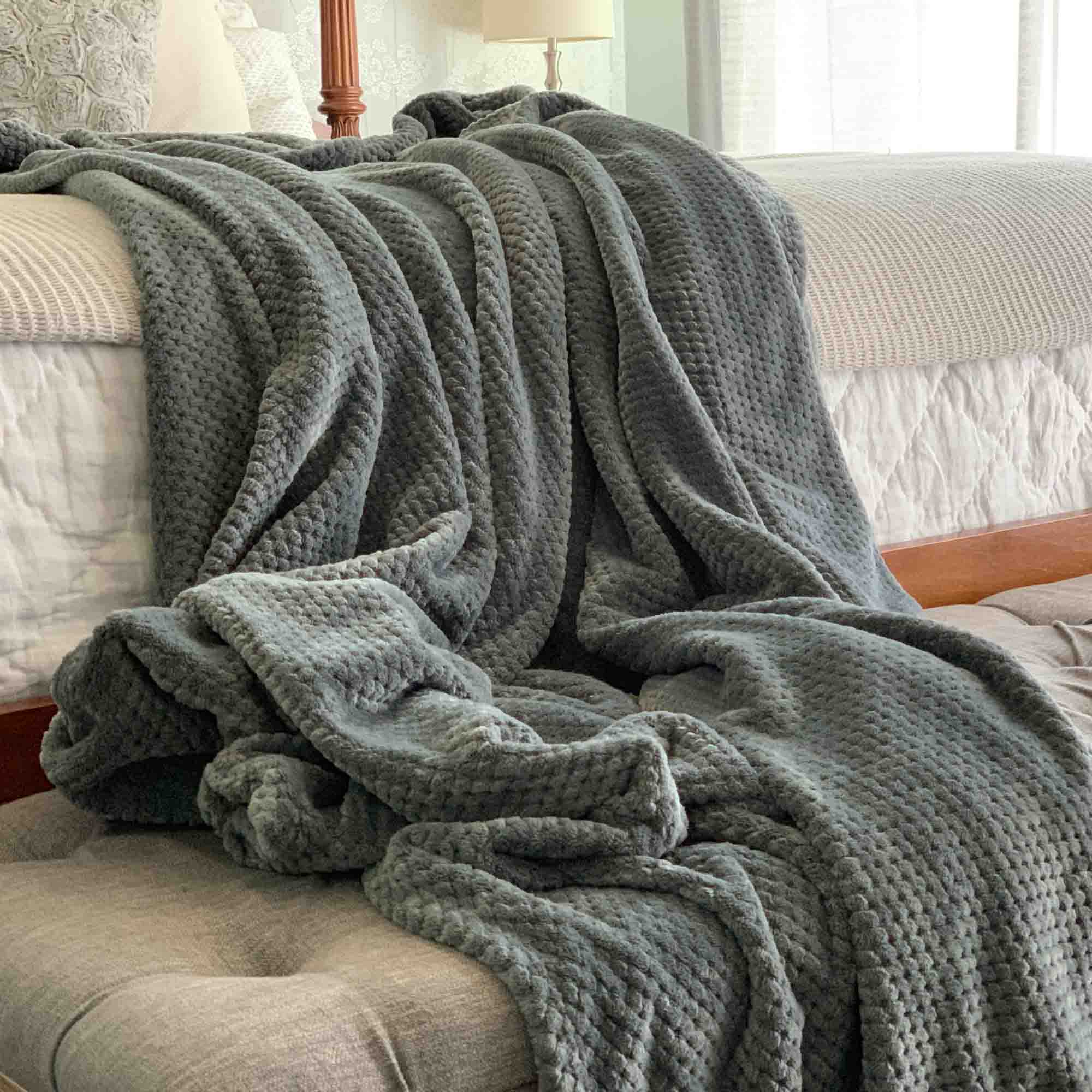 Image of a gray color Microfiber fleece throw blanket draped over a bed and bench