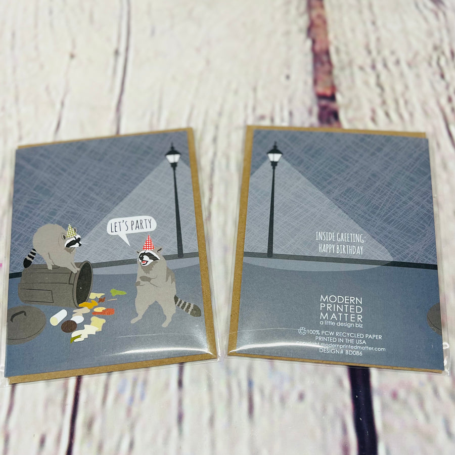 Picture showing the front and back of the card. Front: Picture of two raccoons digging in the trash. One is wearing a party hat saying, 